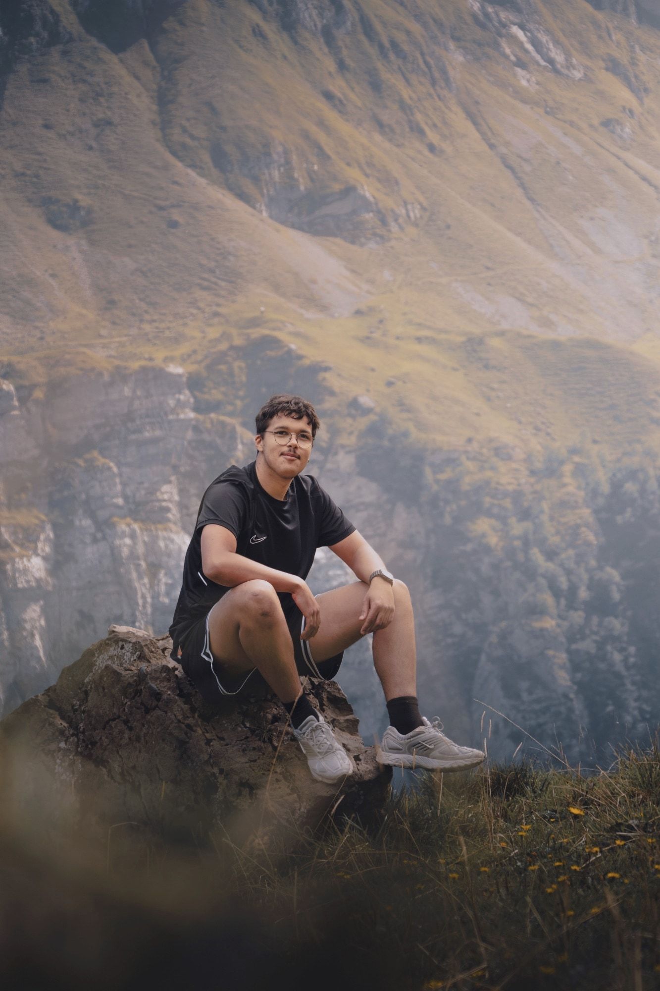 Jeremy Brown sitzt auf einem Felsen vor einer Bergwand